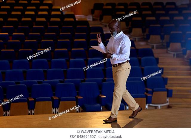 Businessman with holding script walking in a auditorium