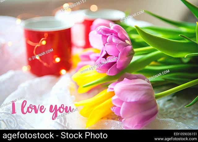 Beautiful morning, two cups of coffee and a bouquet of bright tulips. Inscription I love you