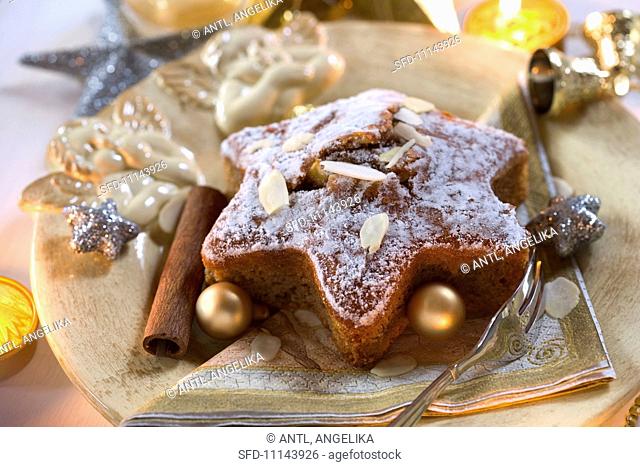 A star-shaped spiced cake with almonds and Christmas baubles on a Christmas angel plate