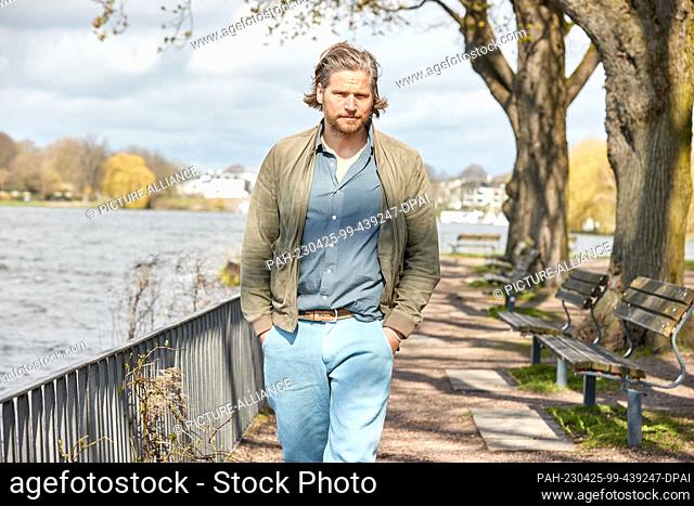 PRODUCTION - 13 April 2023, Hamburg: Sebastian Ströbel, actor, walks along the Außenalster lake during a photo shoot with the German Press Agency