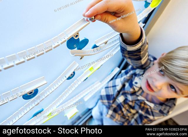 28 November 2023, Bavaria, Nuremberg: Six-year-old Henri plays with the Gecko Run marble game from Franckh-Kosmos at the annual press conference of the German...