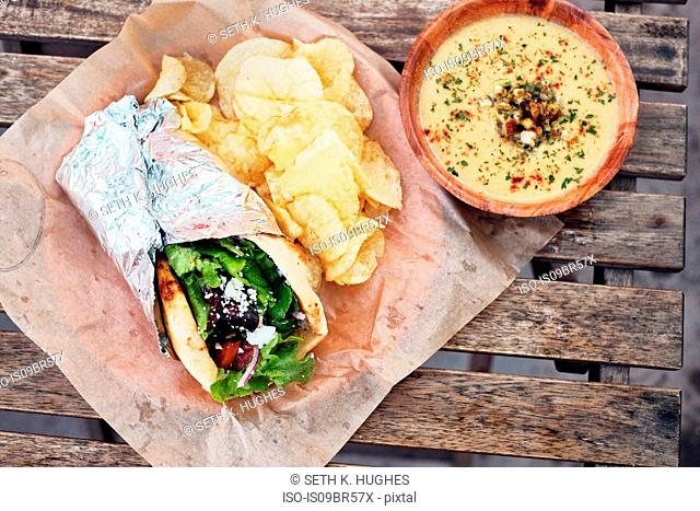 Meal of salad wrap, potato chips and dip