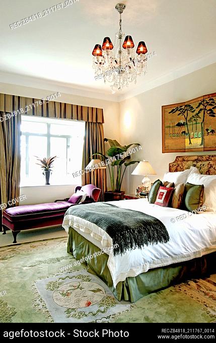 Chandelier above double bed in traditional style bedroom