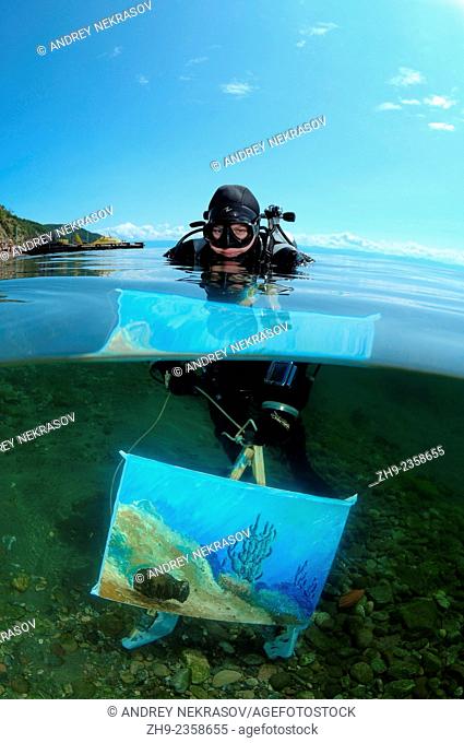 The assistant shows a picture of the artist written by under water artist Yuriy Alexeev (Yuri Alekseev). Lake Baikal, Listvyanka, Irkutsky District