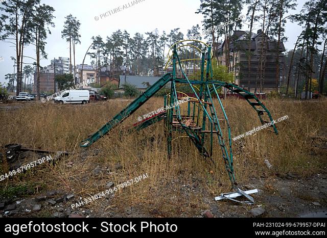 20 October 2023, Ukraine, Irpin: Equipment of a destroyed children's playground stands in high grass. The town near Kiev was partially destroyed by heavy...