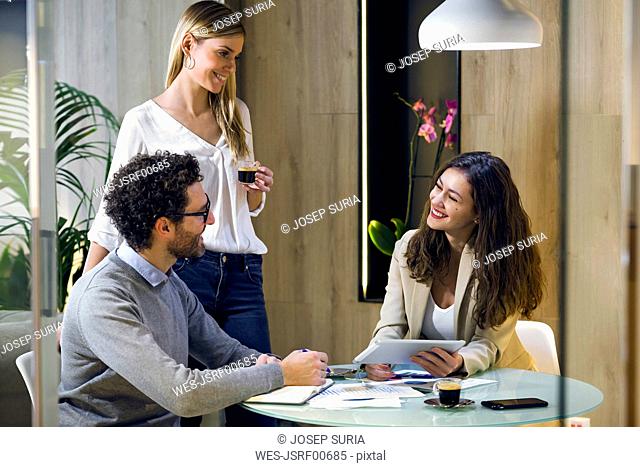 Three happy business people having a meeting in modern office