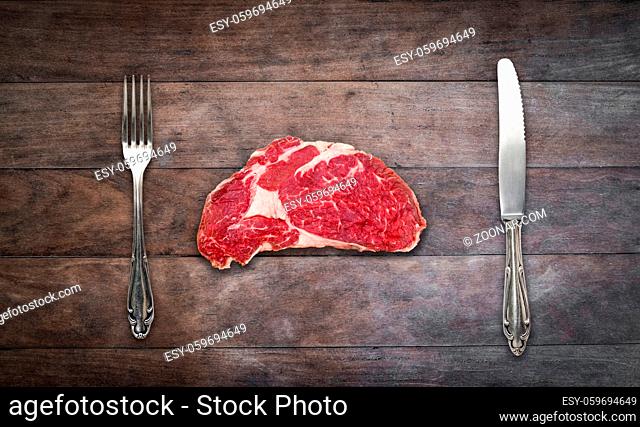 slice red meat / raw steak with knife and fork