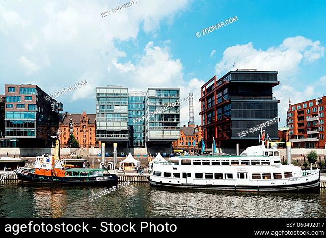 Hamburg, Germany - August 7, 2019: Cityscape of Sandtorhafen canal with ships moored on the harbour and luxury residential modern buildings