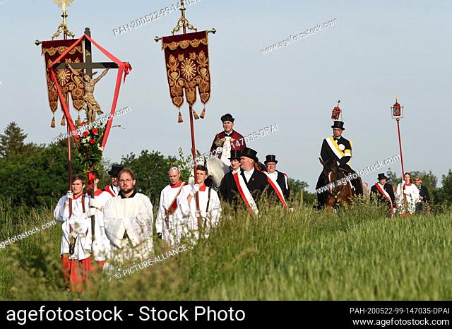 22 May 2020, Baden-Wuerttemberg, Weingarten: Dean Ekkehard Schmid (centre), the Holy Blood Rider, holds the Holy Blood relic in his hand while riding a grey...