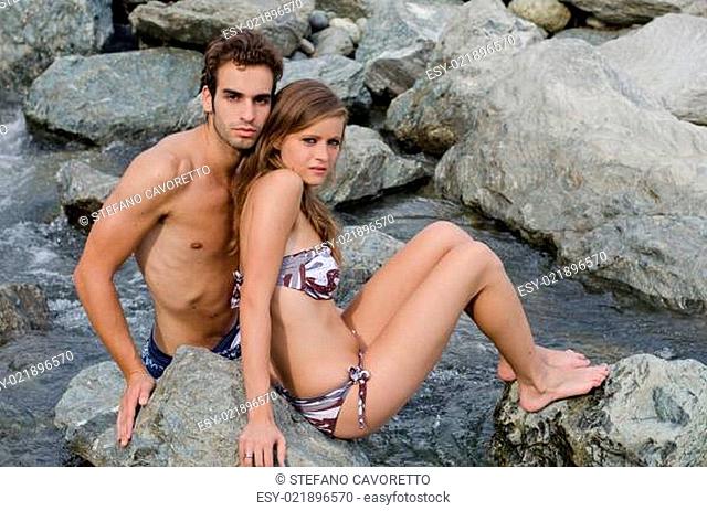 Romantic young couple in swimming suit on rocks