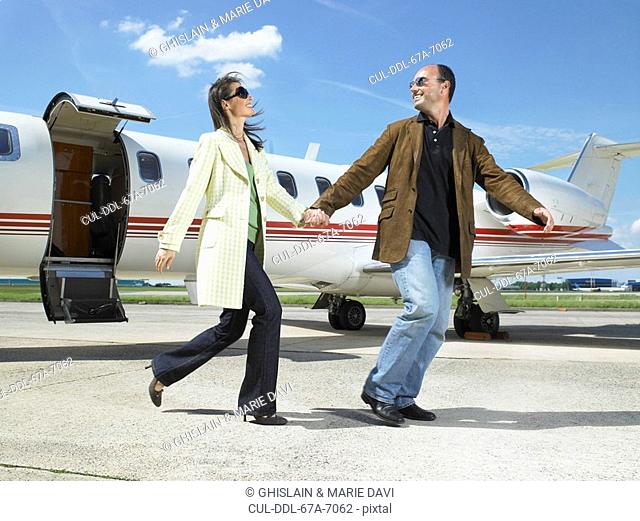 Happy couple running out of private jet