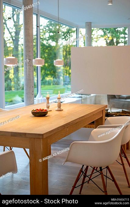 Dining table in a modern living ambience with a view of the countryside in the evening mood