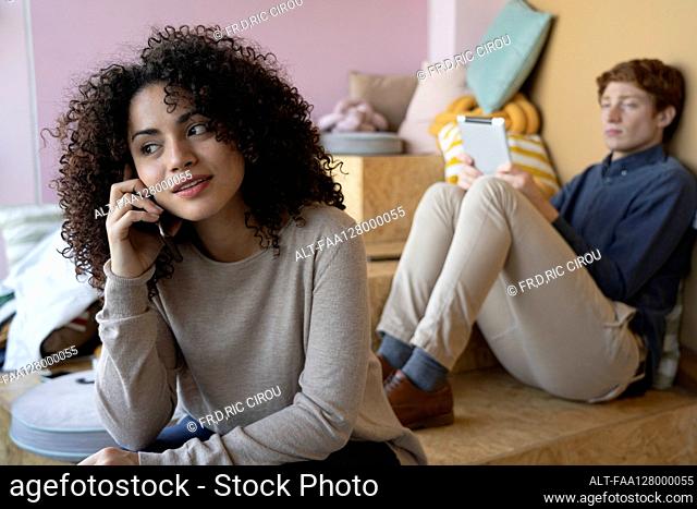 Smiling young woman talking on smart phone in office