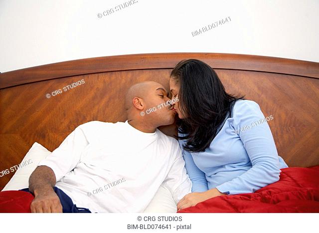 Antiguan man kissing wife in bed