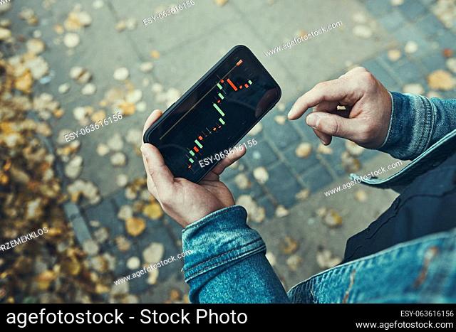 Person investing trading on stock cryptocurrency market using investing application on smartphone. Stock market investment in hand