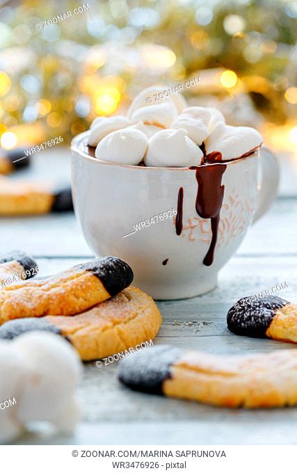Cup of hot chocolate, almond cookies and sieve with icing sugar on white wooden table, selective focus