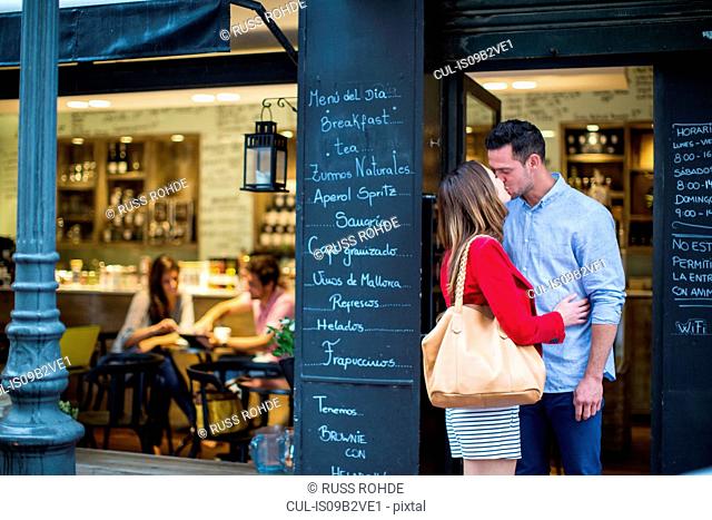 Romantic couple kissing outside cafe