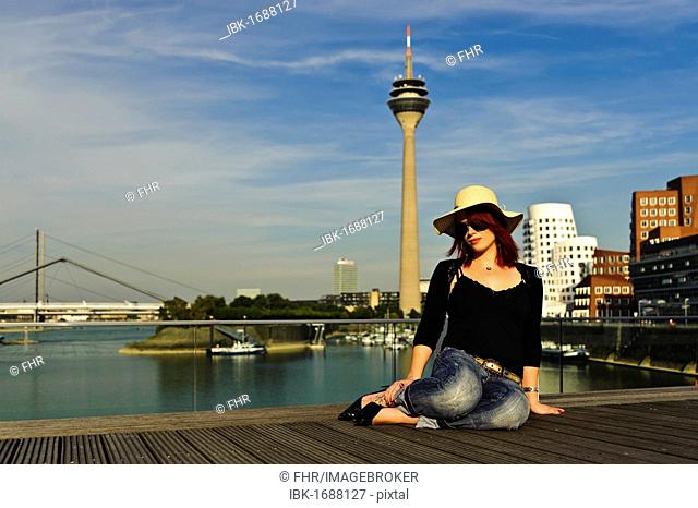 Young woman against the backdrop of Media Harbour in the evening sun, Duesseldorf, North Rhine-Westphalia, Germany, Europe