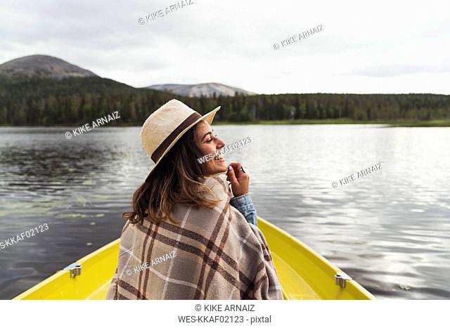 Finland, Lapland, happy woman wearing a hat on a boat on a lake