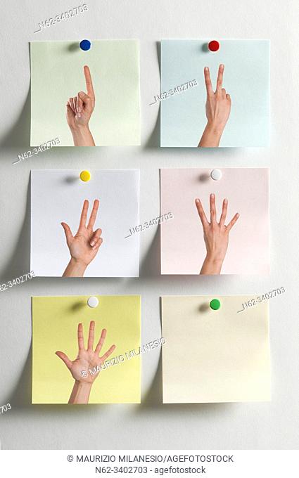 Five colorful Post It messages fixed to the wall with images of fingers indicating numbers and an empty one