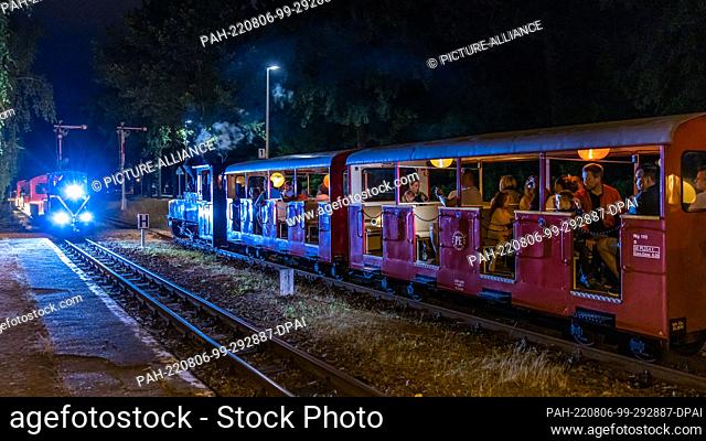 05 August 2022, Brandenburg, Cottbus: During the so-called light rides of the Cottbus park railroad, one train pulls out of a station while another train pulls...