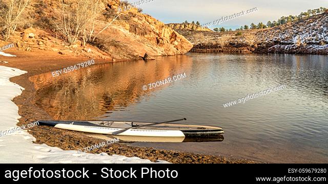 stand up paddleboard in winter scenery on a calm lake at Colorado foothills (Horsetooth Reservoir)