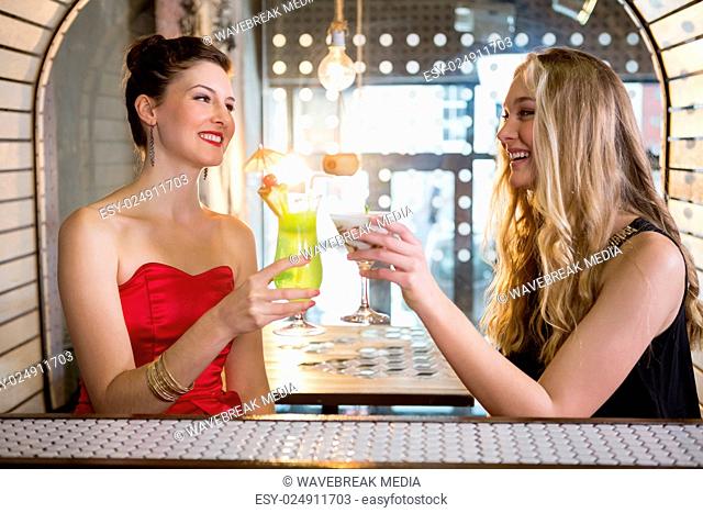 Female friends toasting a glass of cocktail in bar