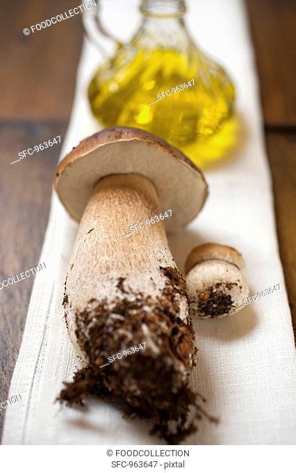 Ceps in front of a carafe of olive oil on linen cloth