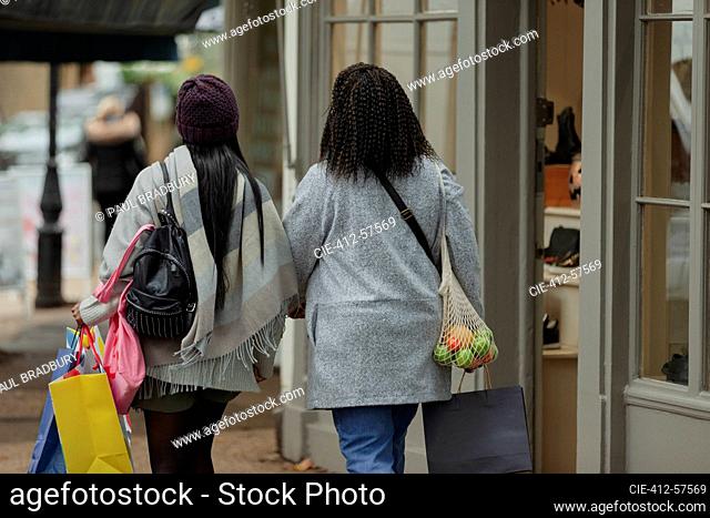 Mother and daughter with shopping bags walking on sidewalk