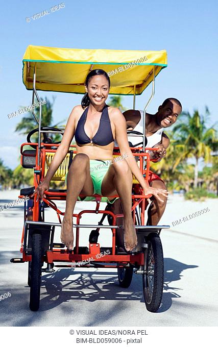 Multi-ethnic couple riding in pedal cart