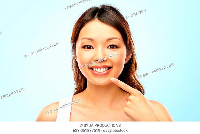happy smiling young asian woman touching her face