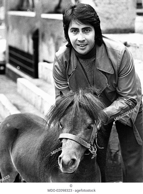 Italian singer and actor Lando Fiorini (Leopoldo Fiorini) stroking a pony. Rome, 1970s