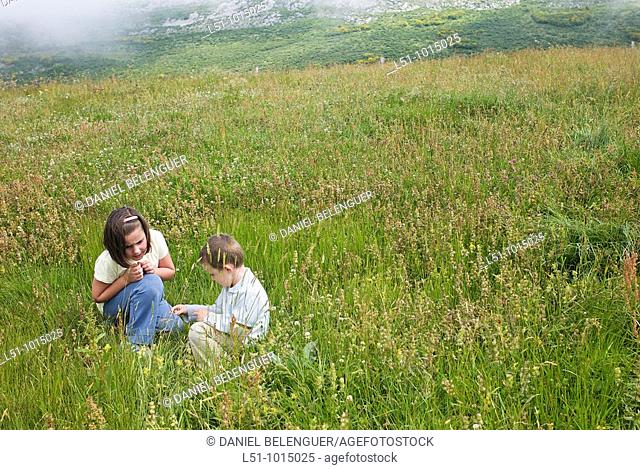 Boy and girl playing on a meadow in the mountains of Somiedo