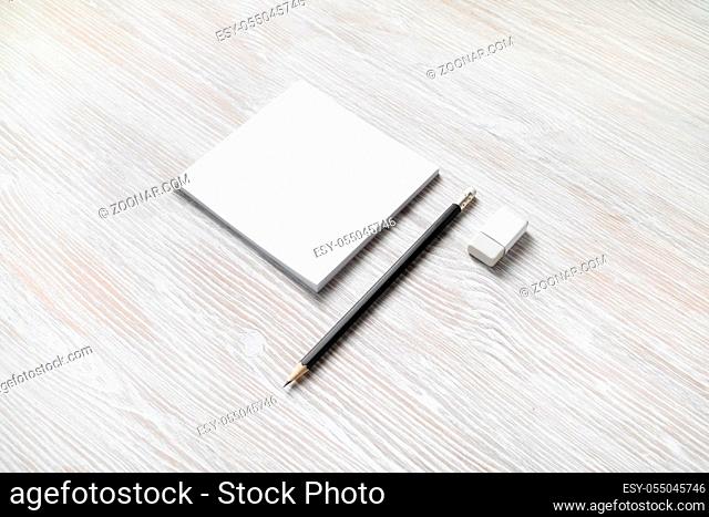 White square notepad, pencil and eraser on light wooden background. Blank stationery template