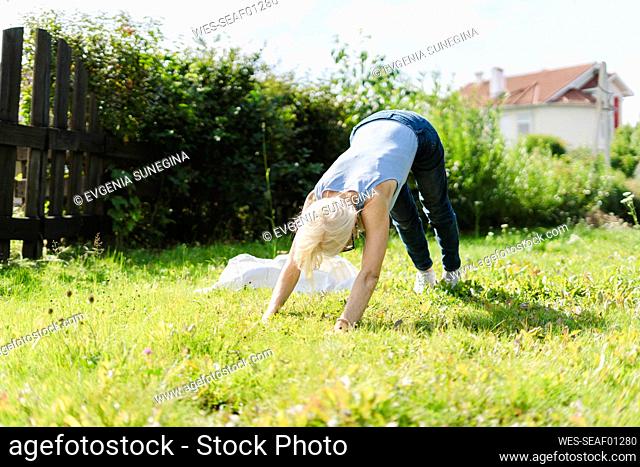 Senior woman exercising on grass in garden