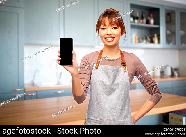 happy woman in apron showing smartphone