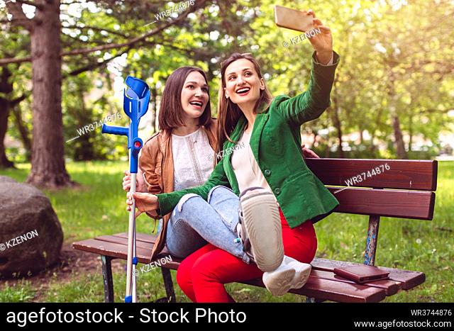 Woman and her friend with a sprained ankle taking a photo or selfie