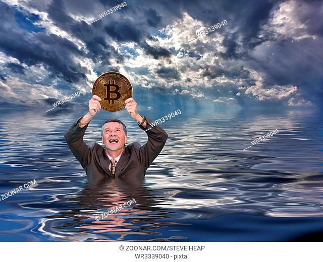 Senior man angry and holding bitcoin as he sinks into water after investing in the cybercurrency