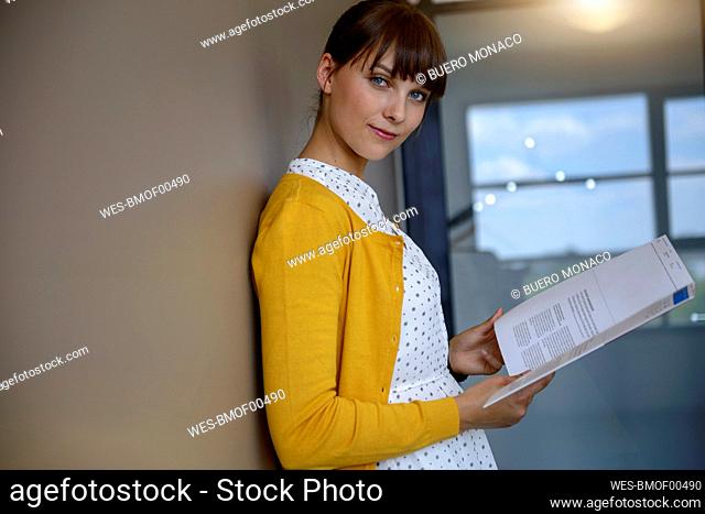 Confident businesswoman with bangs reading document at office