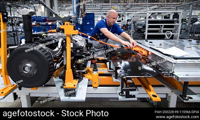 25 February 2020, Saxony, Zwickau: An employee of Volkswagen Sachsen in Zwickau wires the battery on a line for the new VW ID.3