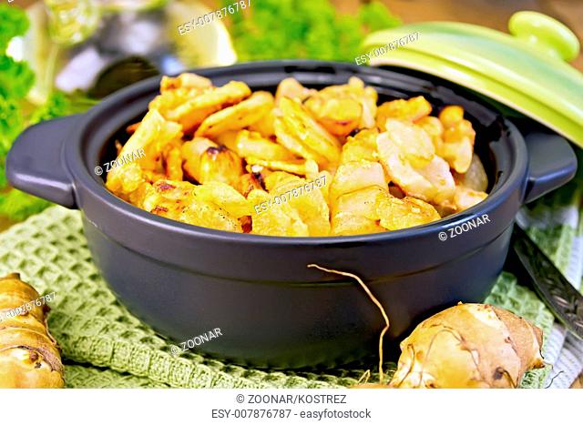 Jerusalem artichokes roasted in pan with lid on board