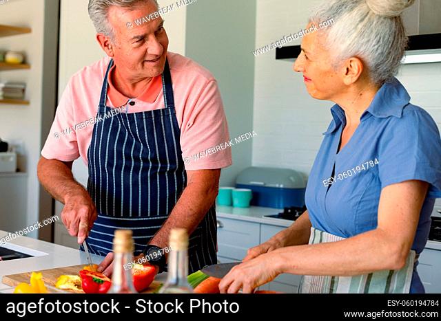 Happy caucasian senior couple standing in kitchen and preparing meal together