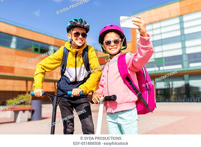 happy school kids with scooters taking selfie