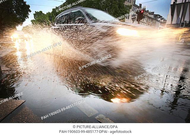 03 June 2019, Duesseldorf: A car drives in the state capital through a puddle of water on the road. A low pressure area brings hot and humid air from the...
