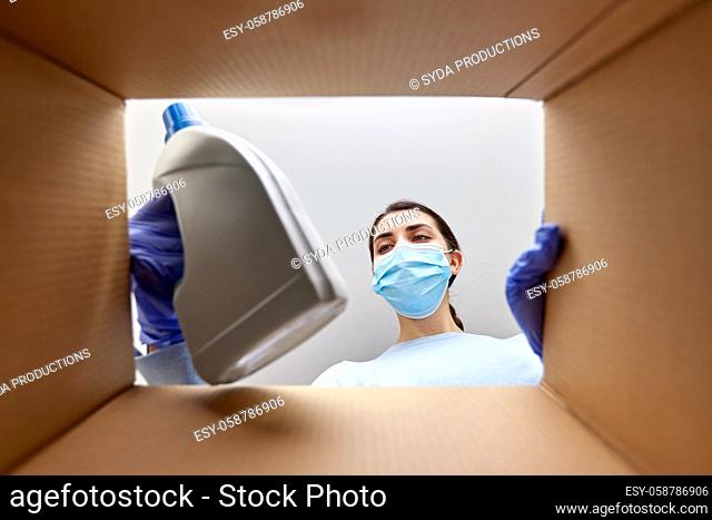 woman in mask taking cleaning supplies from box