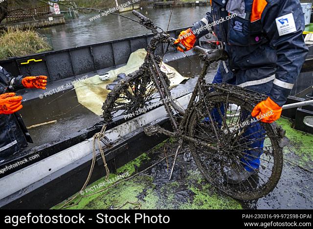 PRODUCTION - 13 March 2023, Berlin: Employees from the Water and Shipping Authority load a bicycle retrieved from the water onto a floating container during a...