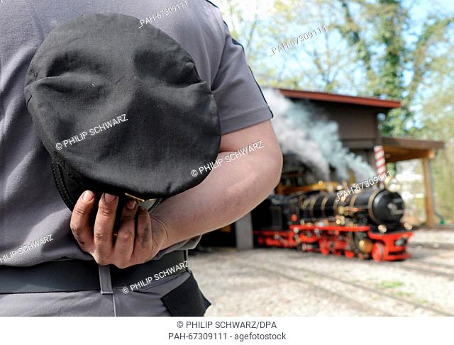Engine driver Thomas Stegmueller holds his uniform cap in front of an historic steam locomotive from 1928 in Killesberg park in Stuttgart,  Germany