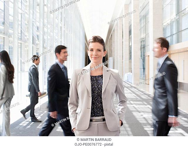 Busy co-workers waking past businesswoman