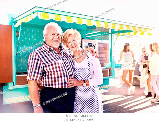 Portrait smiling senior business owners outside sunny food cart