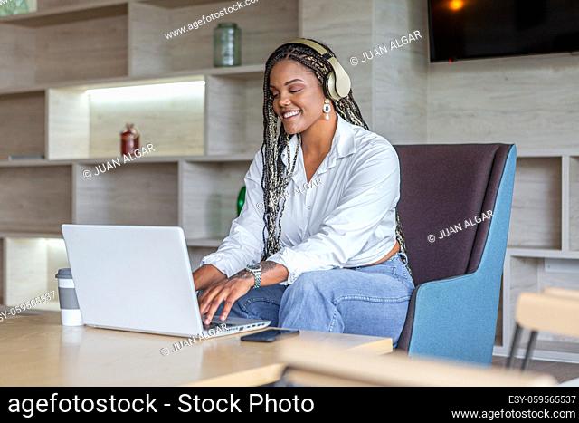 African American woman with headphones using laptop in home. Concept of people in home